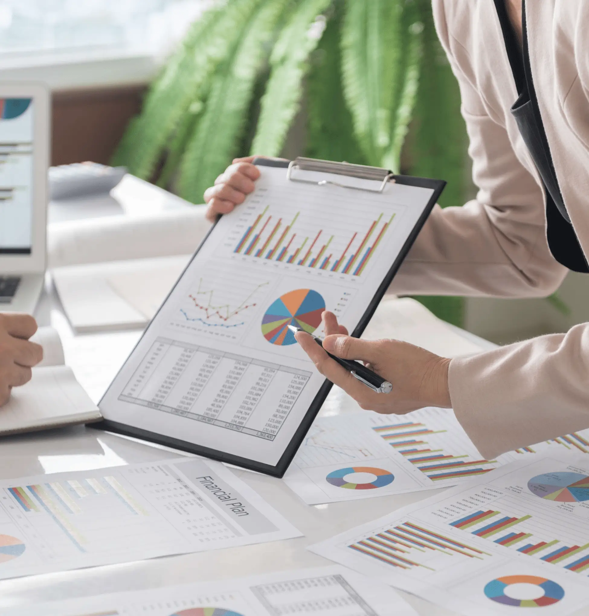 Two people analyzing financial charts on a tablet and papers.